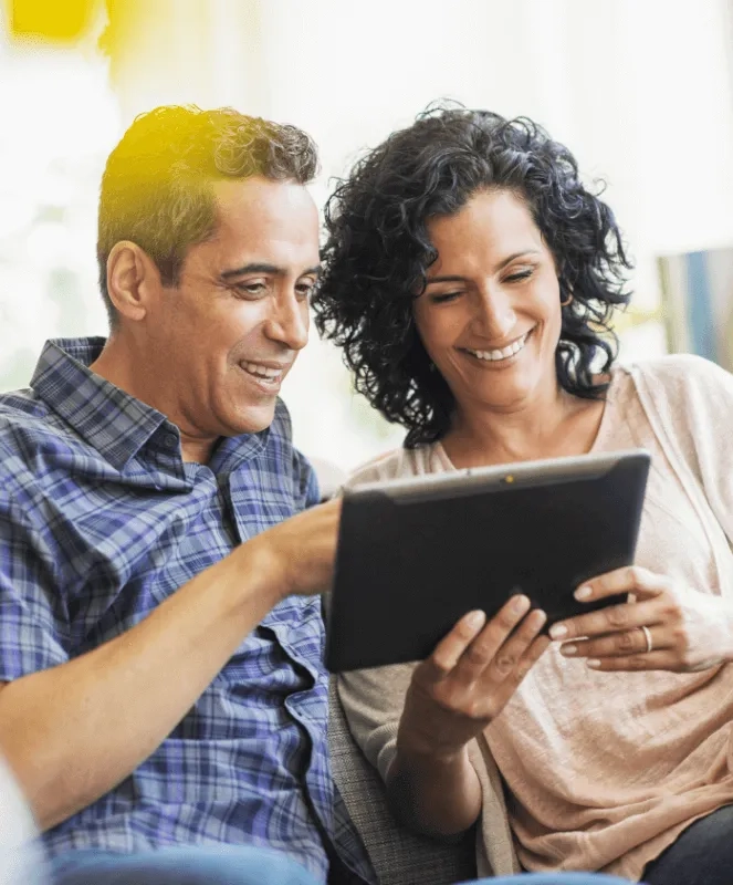 couple smiling, reading tablet